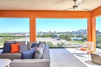 A living room with a grey couch and orange pillows.